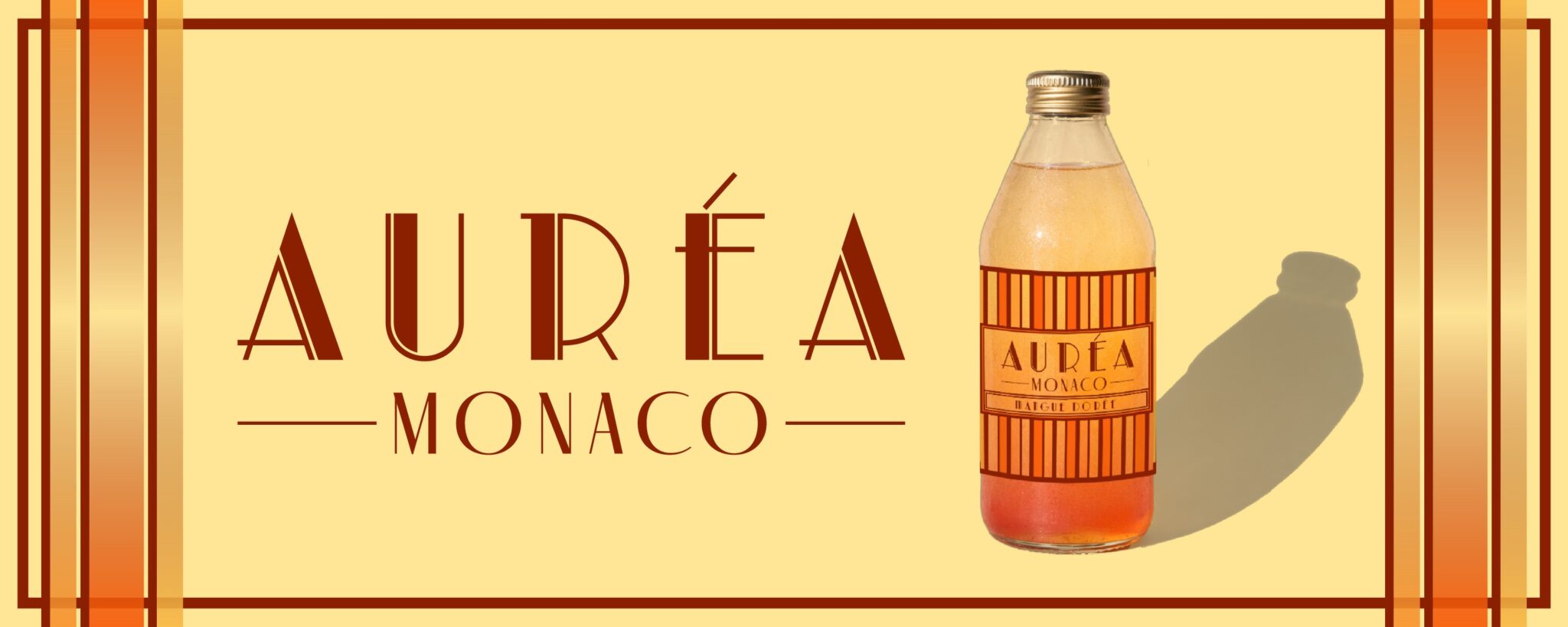 Wide AURÉA Monaco banner in cream and orange with the wordmark and a bottle casting a shadow