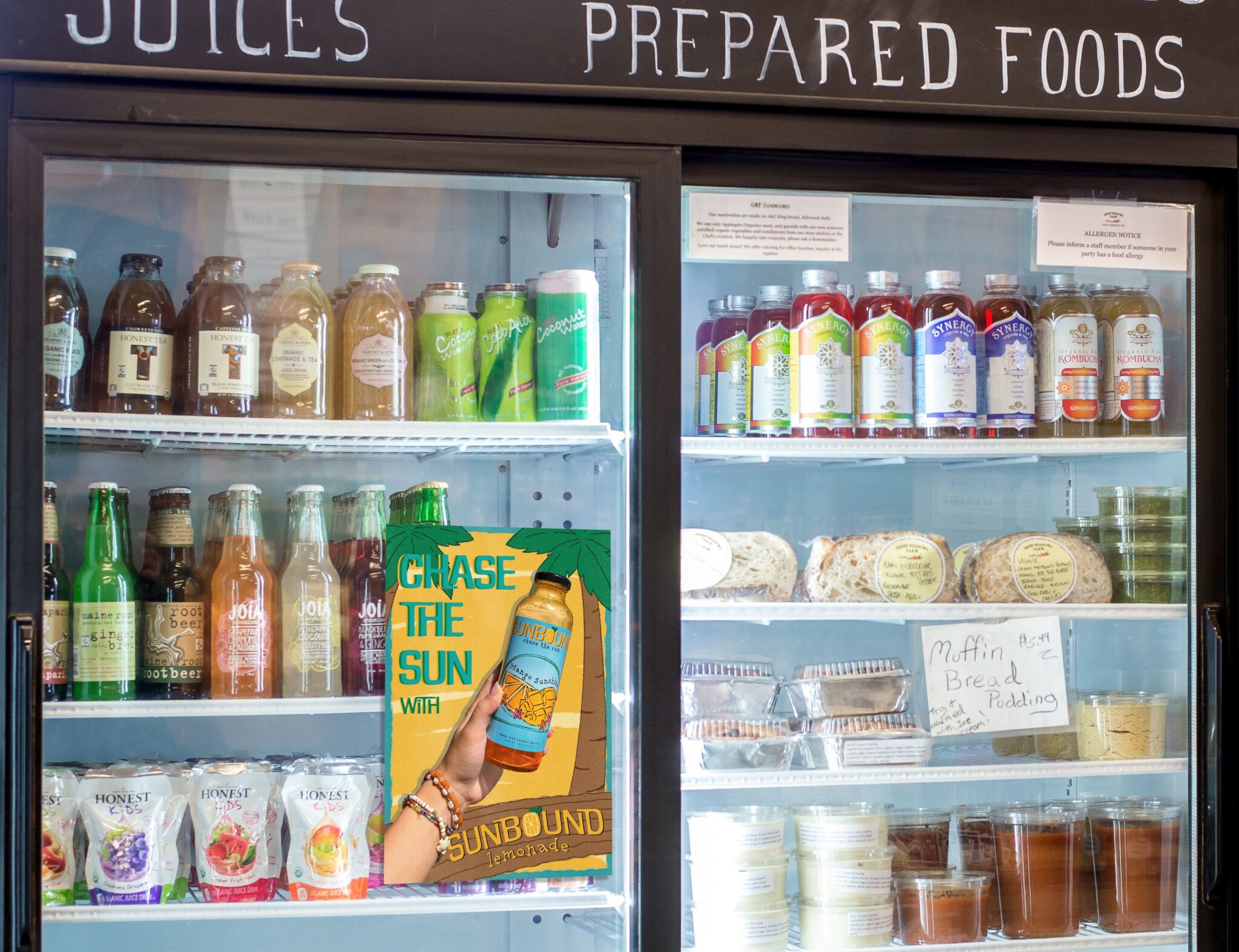 Mockup of the Chase the Sun poster on the glass door of a refrigerated drinks case in a shop